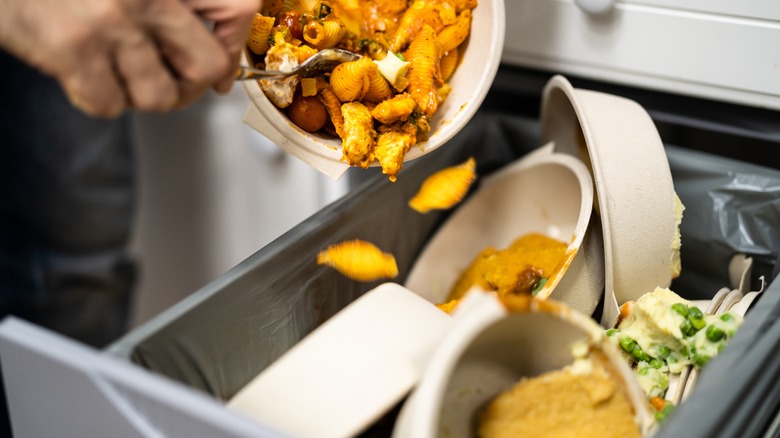 Person dumping pasta into a garbage can