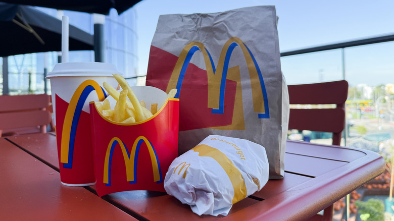 McDonald's bag, drink, fries, and wrapped sandwich on outdoor table