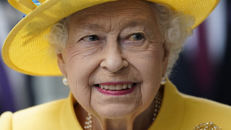 Queen Elizabeth smiling in yellow hat