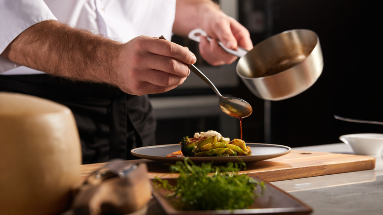 Chef drizzling sauce over dish 