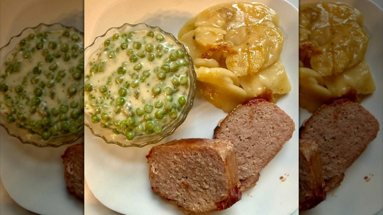 Ham loaf dinner with potatoes and creamy peas on a white plate