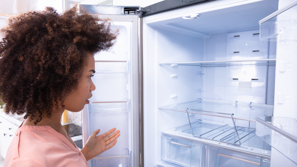 Woman staring into empty refrigerator