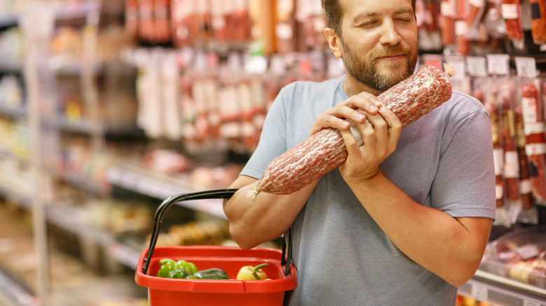 Supermarket customer smelling meat product