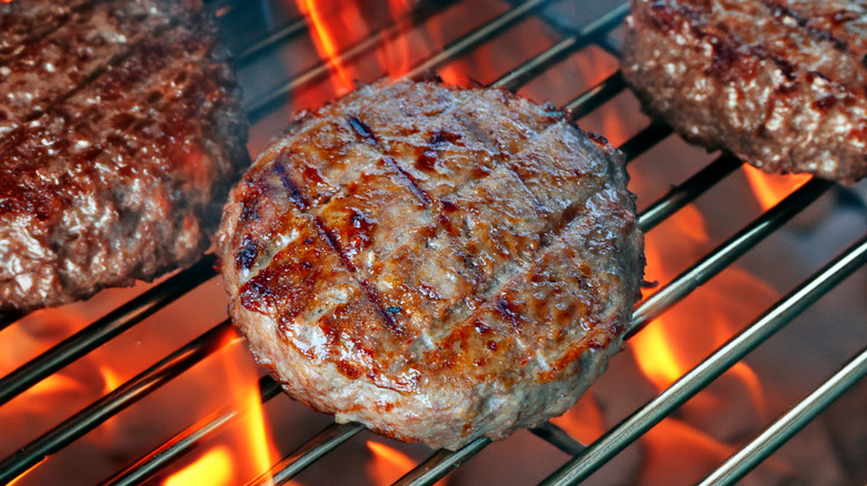 Burger patties on flaming grill