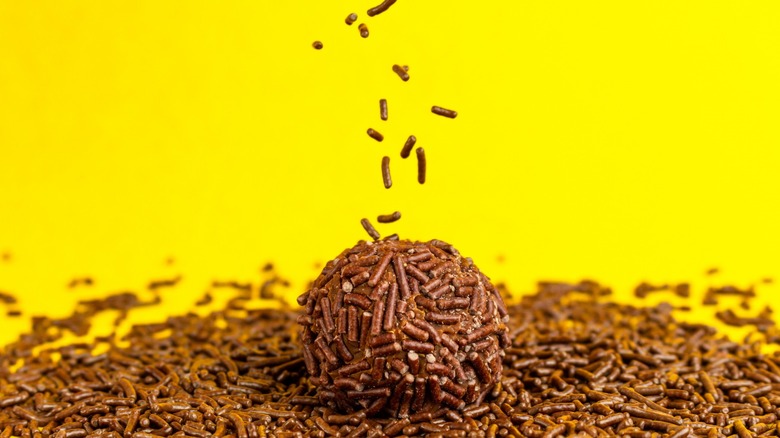 Brigadeiro in a bed of sprinkles on a yellow background 