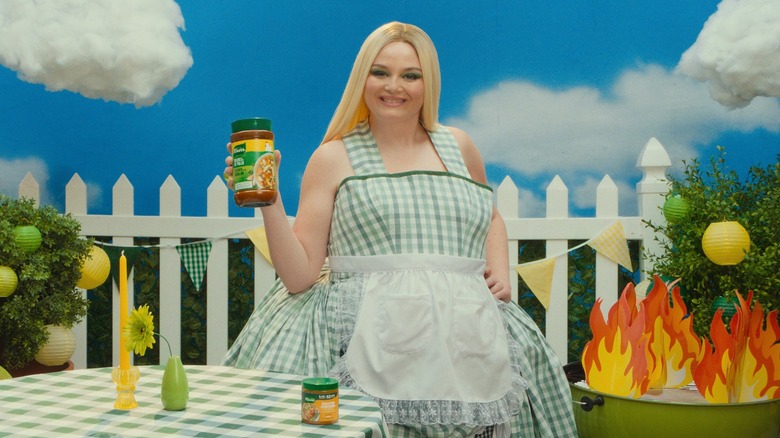 Comedian Meg Stalter posing with Knorr products in artificial backyard environment.