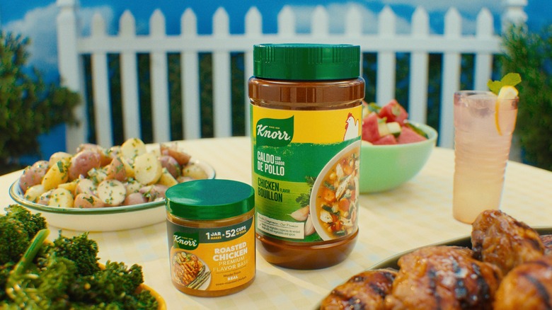 Knorr seasoning containers on table with roasted chicken, seasoned potatoes, and other foods.