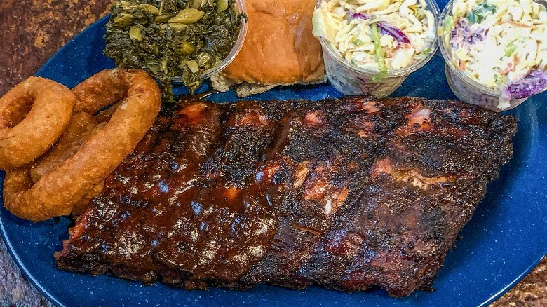 Memphis-style barbecue ribs, onion rings, and sides on a blue plate