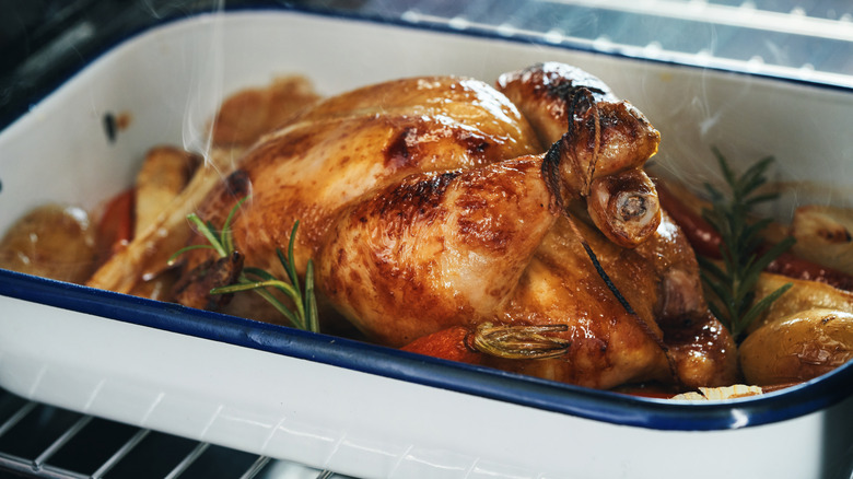 Roast chicken in an oven dish with herbs and root vegetables