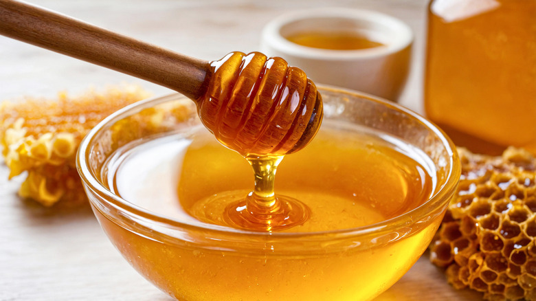 A bowl of honey with a wooden dipper