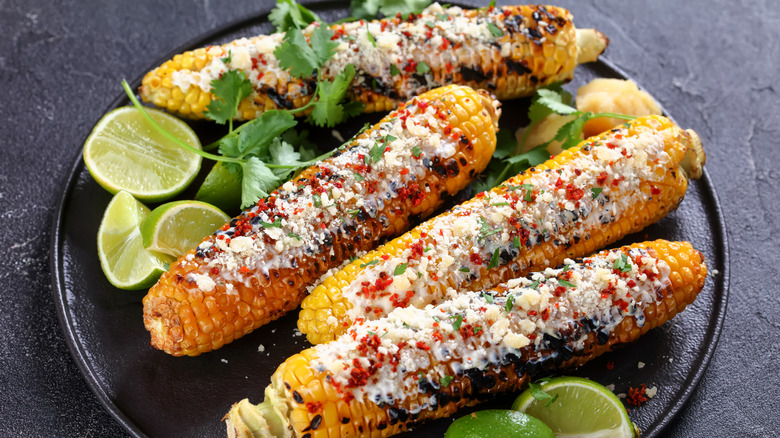 Mexican street corn on the cob on plate with limes