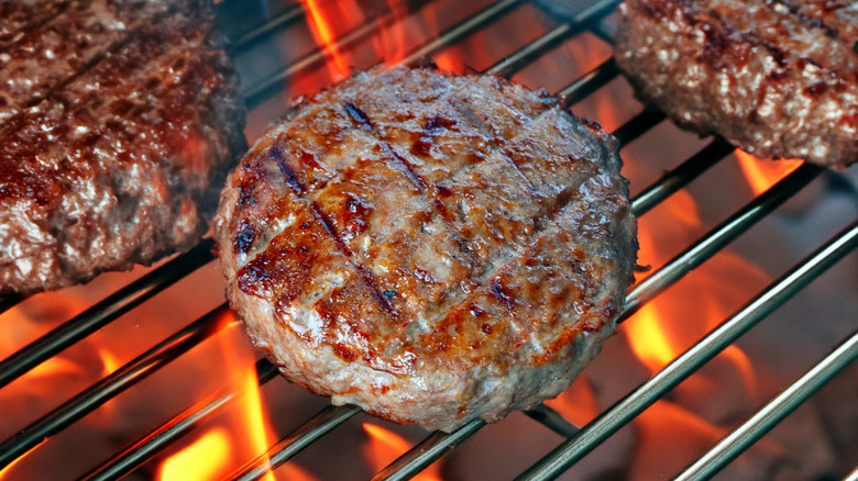 Burger patties on flaming grill