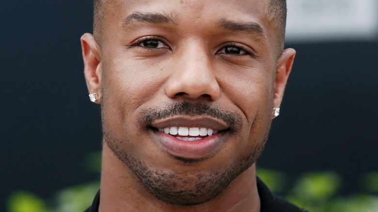 Michael B. Jordan with wide smile and diamond earrings