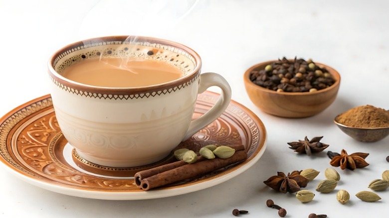 Chai in a mug on a plate surrounded by dry spices