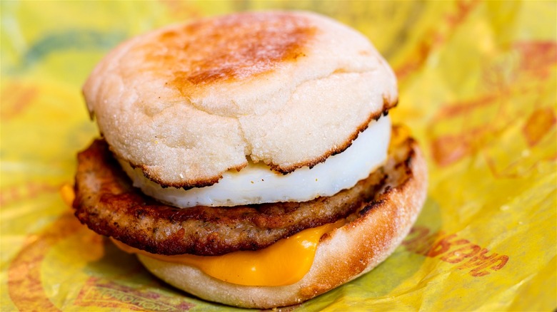 A McDonald's sausage McMuffin with egg on top of a freshly opened wrapper