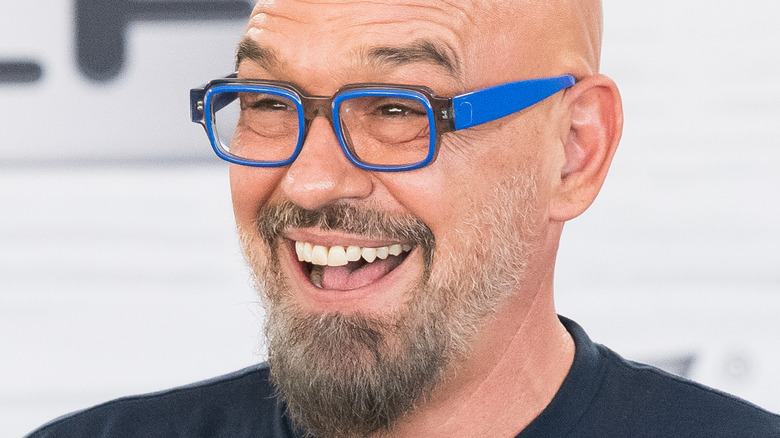 Michael Symon smiling widely in blue glasses