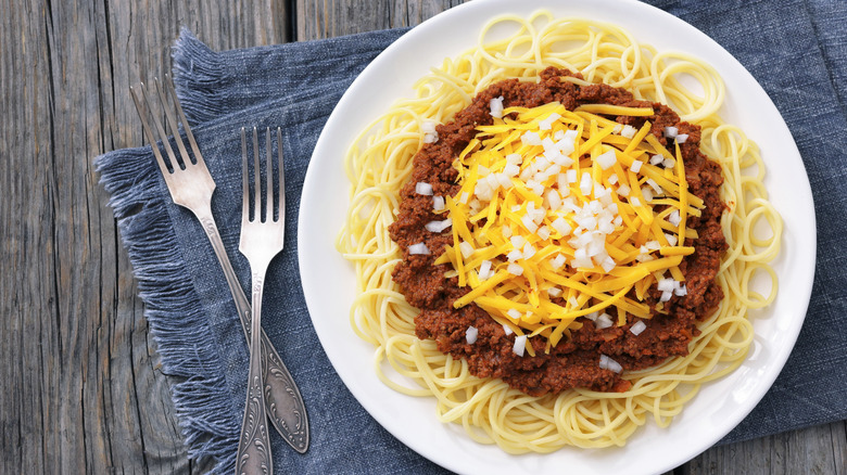 A plate of chili on top of spaghetti