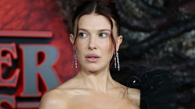 Actress Millie Bobby Brown with hair up and dangly earrings