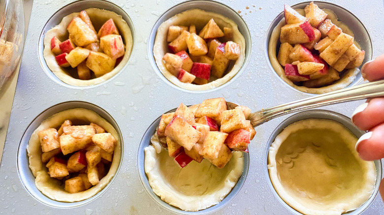 putting the apple pie mixture into crust