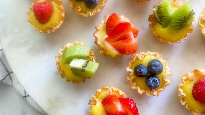 Woman taking mini fruit tart