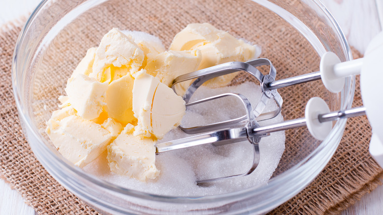 Butter and sugar in a glass bowl with a hand mixer