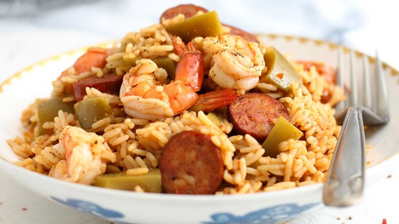 Sliced sausage and shrimp with rice and fork in bowl