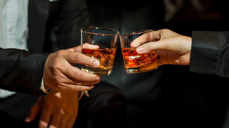 People toasting with whiskey glasses