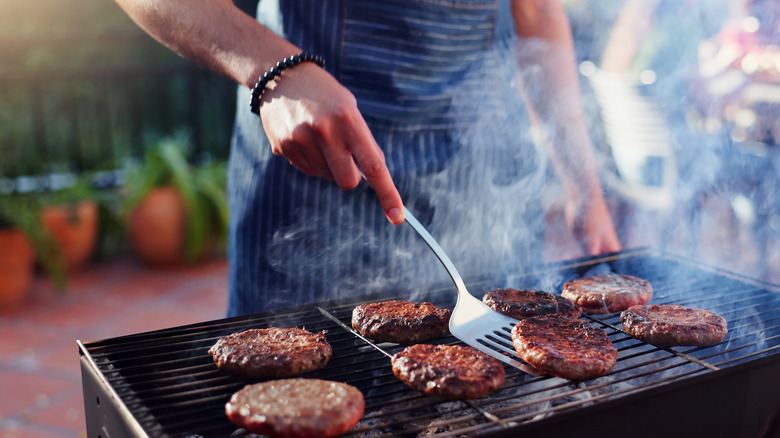 man flipping burgers on grill