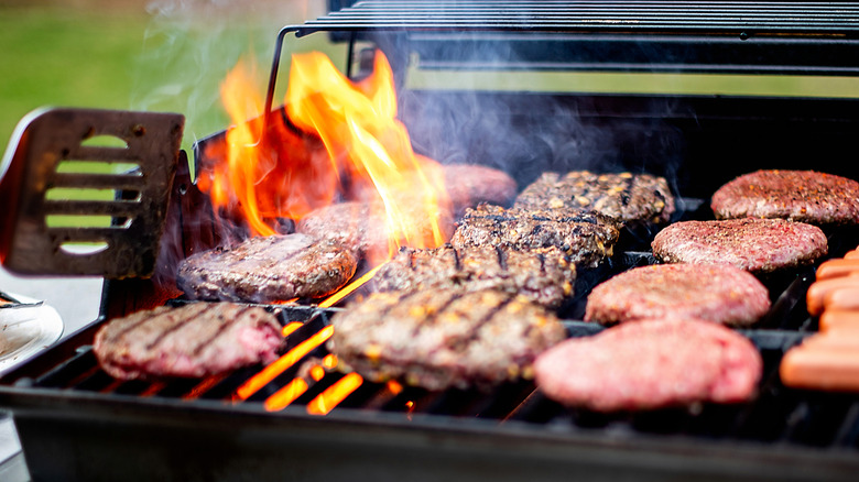 flames leaping over burgers on grill