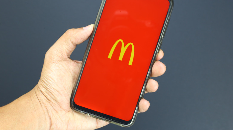 orang memegang telepon dengan aplikasi McDonald's