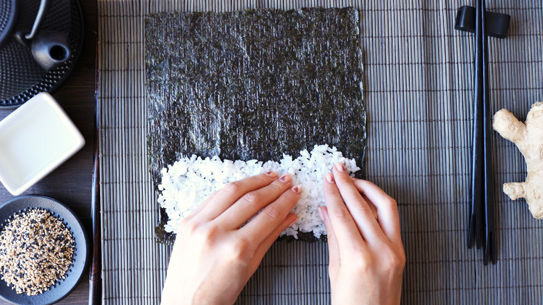 hands preparing sushi on mat