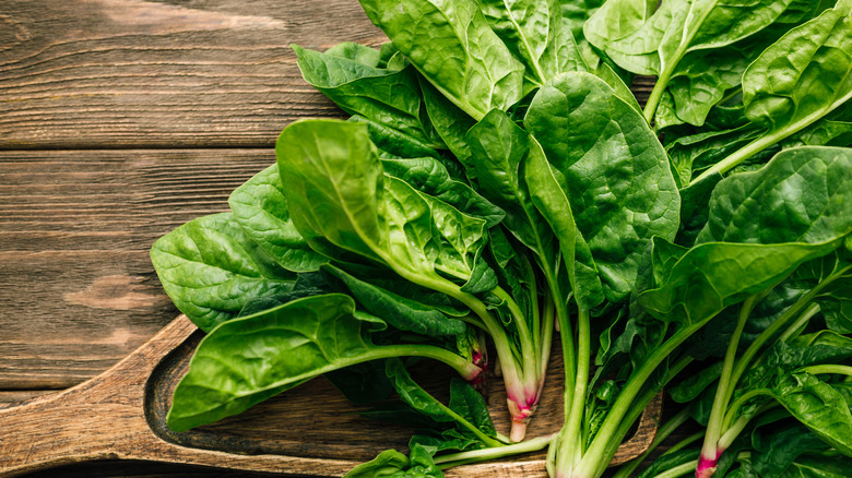 bunch of fresh spinach on wooden background