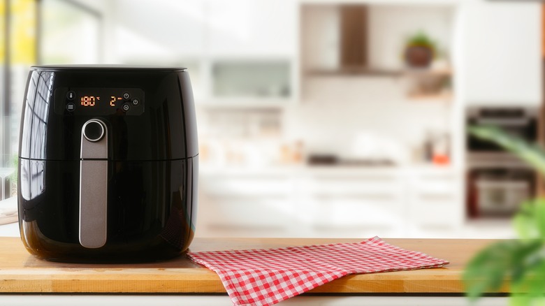 Air fryer sitting on a wooden board on a kitchen counter
