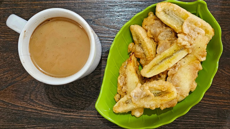 Fried bananas on a leaf-shaped plate with cup of coffee