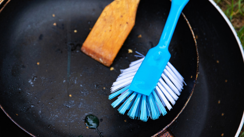 washing nonstick pan with scrubbing brush