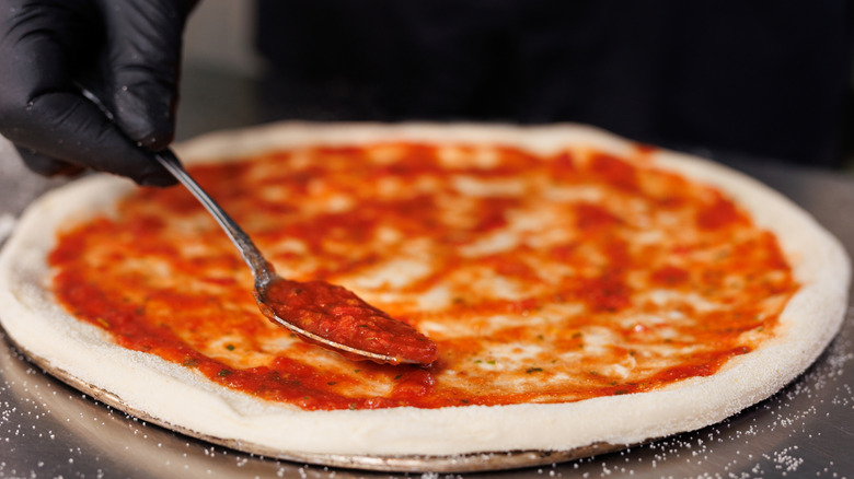 Sauce being spread onto pizza base