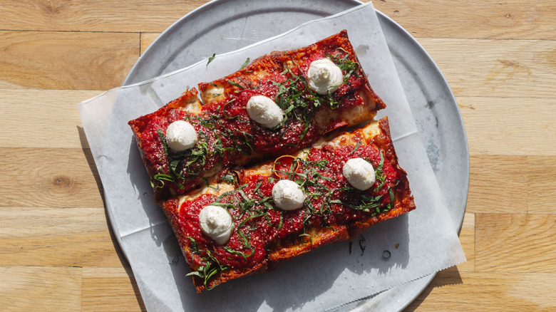 Detroit style pizza with sauce on top of the crust