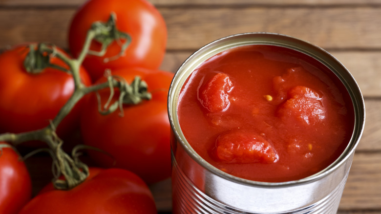 Fresh and canned tomatoes on wooden table