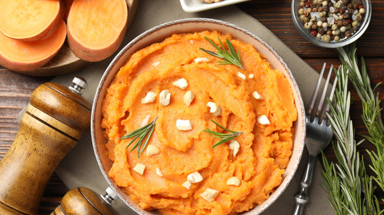 Mashed sweet potato surrounded by herbs and peppercorns