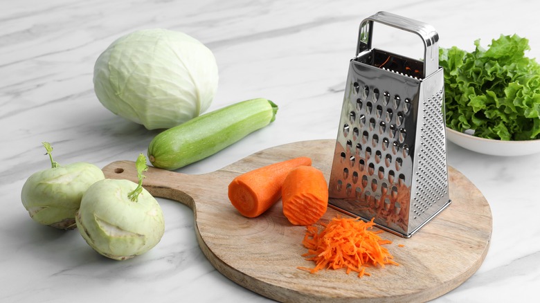 box grater on cutting board next to vegetables