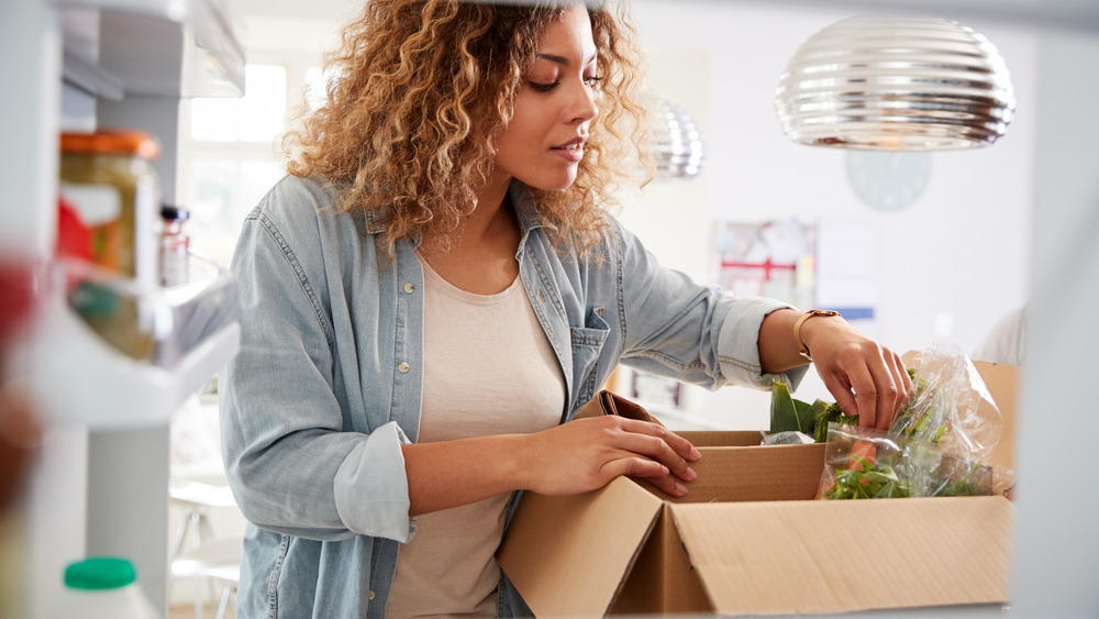 woman unpacking groceries in refrigerator