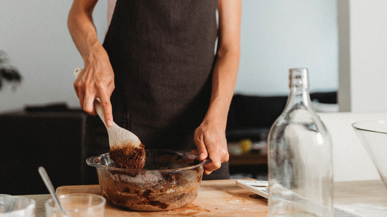 Woman's hands preparing brownie mix in a glass bowl
