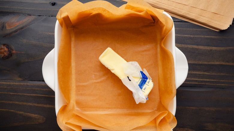 A stick of butter in a parchment-lined brownie pan