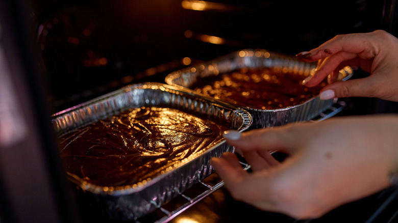 Trays of brownie batter being put in oven