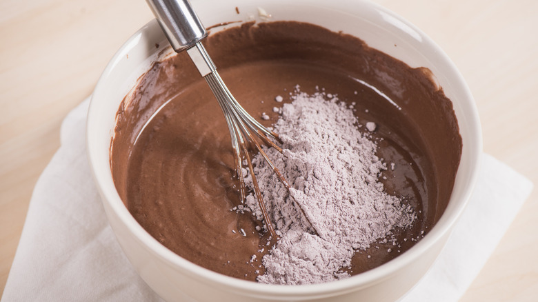 Brownie ingredients mixed in a bowl with some powdered mix on top