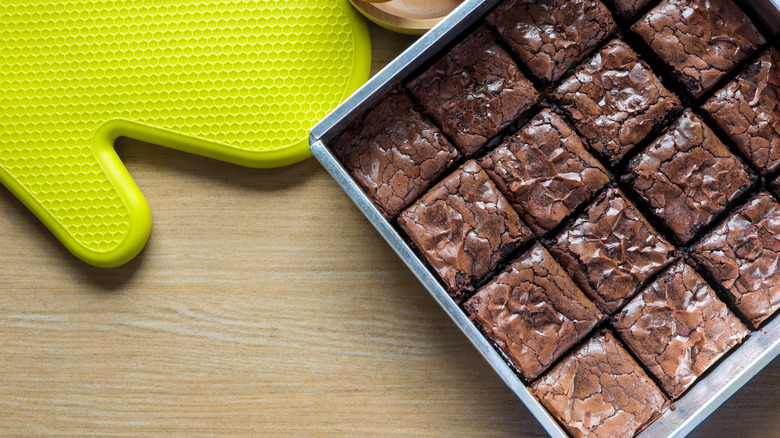 Baked brownies in a pan with a green oven mit