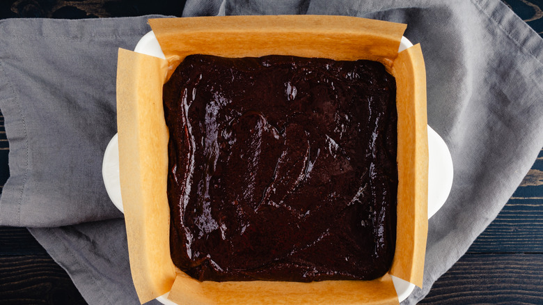 Brownie batter in a baking pan with a gray napkin underneath