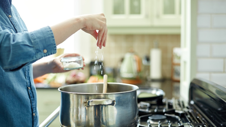 Person seasoning food in pan