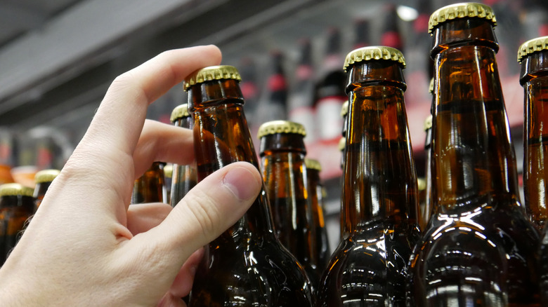 Hand picking bottle of beer from shelf