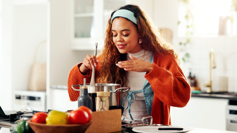 Person stirring pot and smelling food